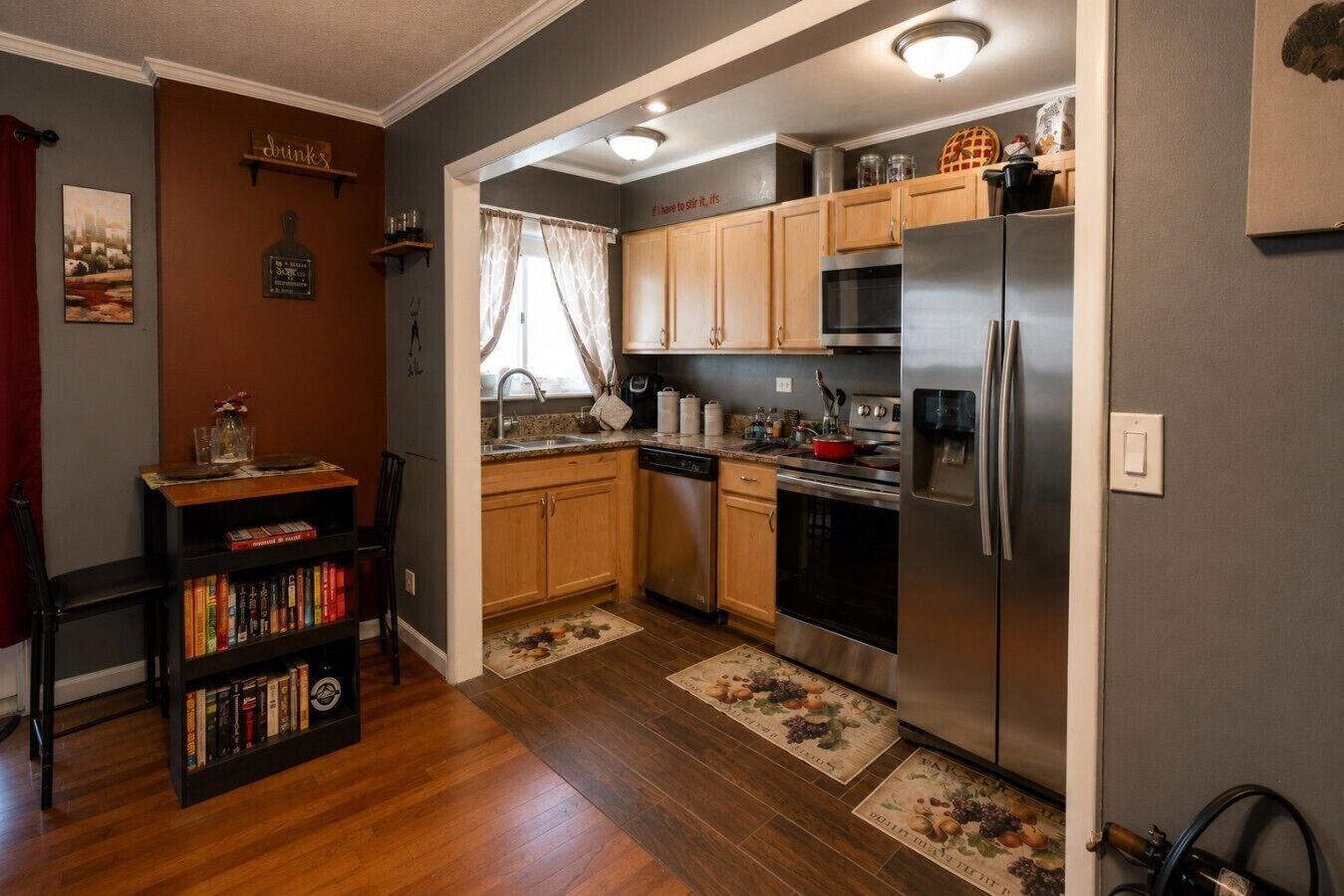Una cocina compacta con gabinetes de madera, un refrigerador de acero inoxidable y un lavavajillas.