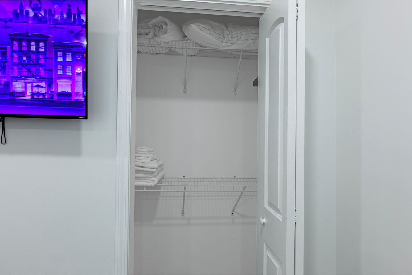 Ein begehbarer Kleiderschrank mit weißer Tür, einem Schuhregal und ordentlich gefalteten Handtüchern.