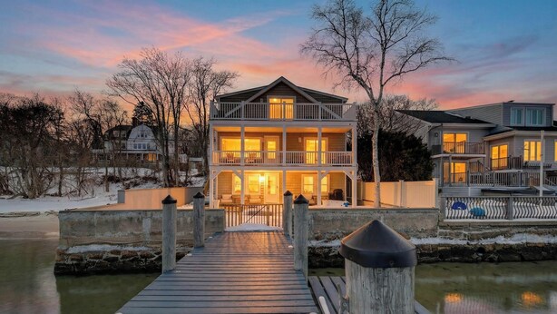 A waterfront property with a wooden dock leading to a multi-story house with balconies and large windows. - Family Waterfront Vacation Estate in New London, CT. (New London)