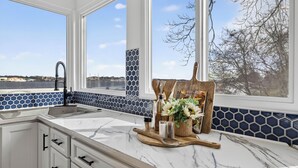 A kitchen with a large window, white cabinets, and a marble countertop. - Family Waterfront Vacation Estate in New London, CT. (New London)
