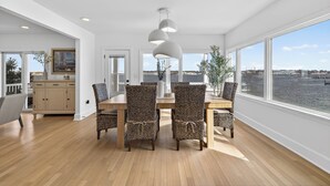 A dining area with a wooden table and wicker chairs, large windows with a view of the water, and a modern pendant light. - Family Waterfront Vacation Estate in New London, CT. (New London)