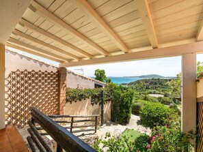 A balcony with a view of a coastal landscape, a pergola, and a wooden railing. - Casetta Nel Blu by Interhome (Villasimius)