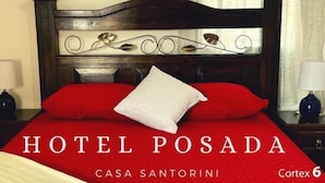 A hotel room with a wooden headboard, red bedding, and a white pillow. The room has a lamp on each side of the bed. - Hotel Posada Casa Santorini (Antigua Guatemala)