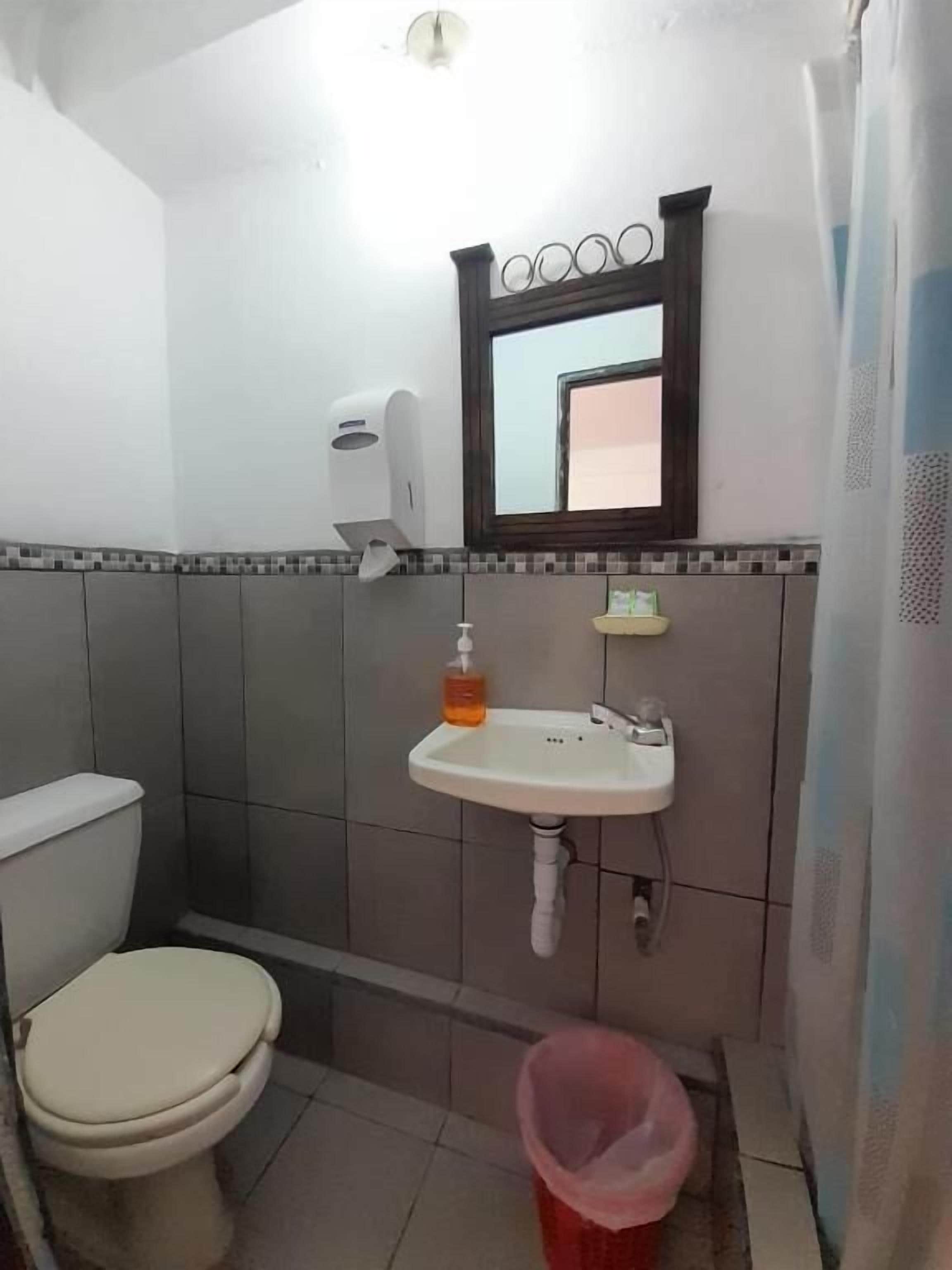 Un baño pequeño con inodoro, lavamanos y un cubo de basura.