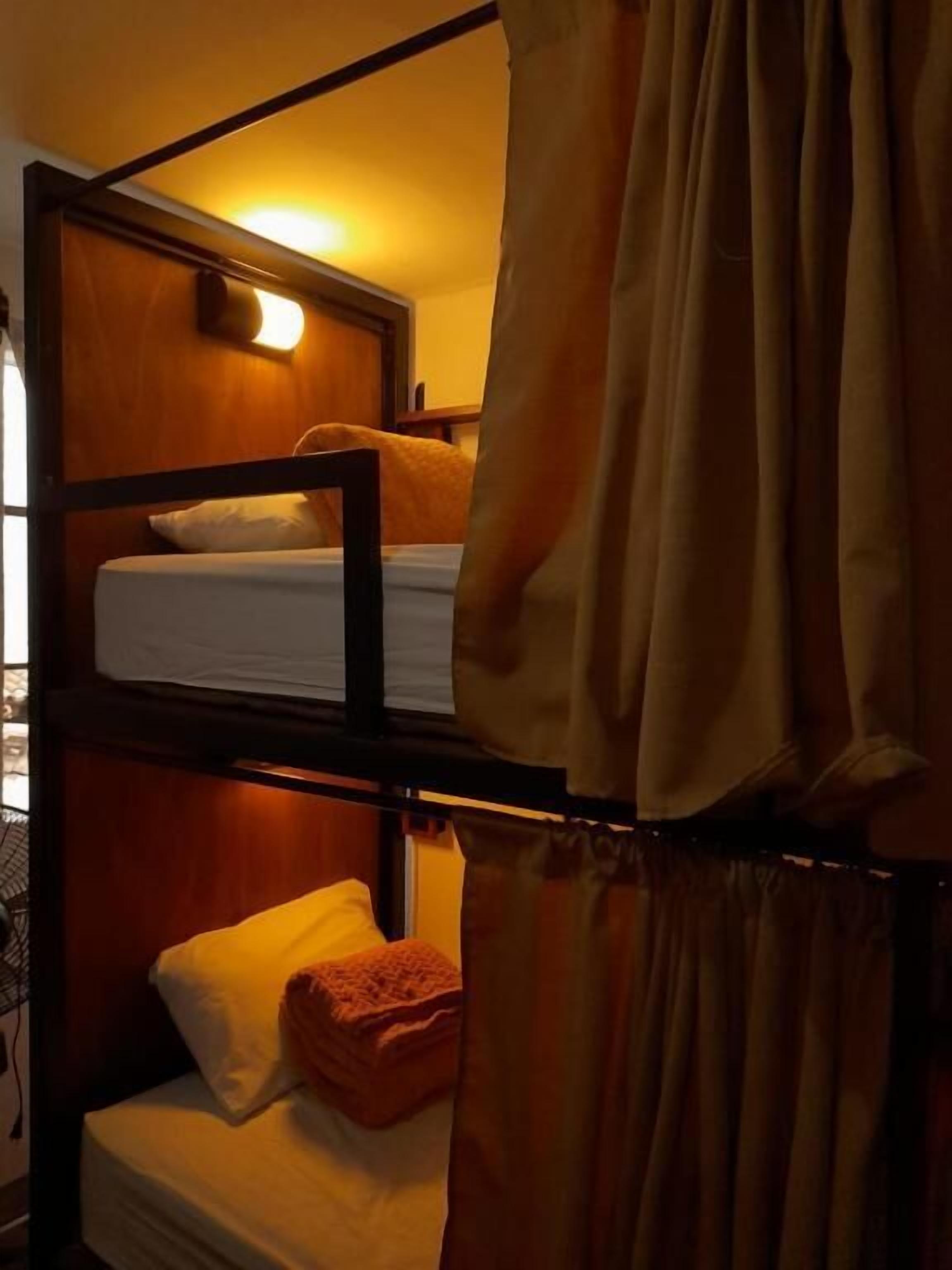 Ein Schlafraum mit Etagenbetten, einem Holzkopfstück, einem Nachttisch und einer Lampe.