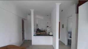 A spacious living area with a kitchen in the background, a dining table, and a sofa.