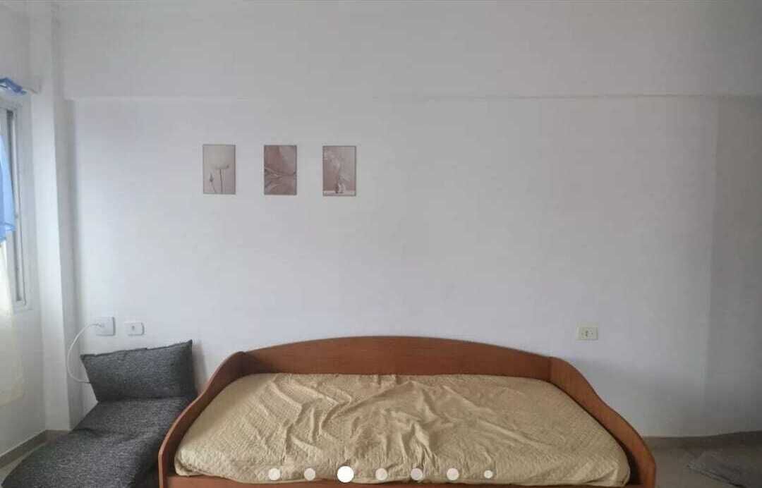 A room with a bed, a chair, and three framed pictures on the wall.
