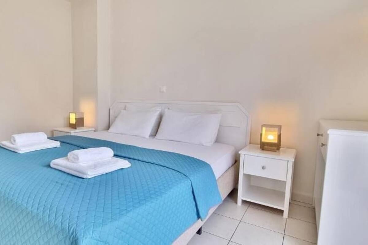 Een hotelkamer met een bed, nachtkastje en een witte kast.