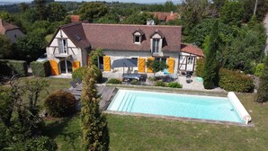 Una casa con piscina, un patio amueblado al aire libre y un jardín.