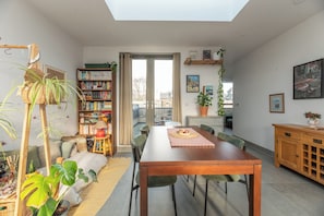 A dining area with a wooden table, chairs, and a view of the city through large windows.