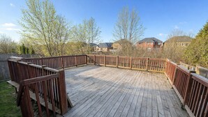 A wooden deck with railings, surrounded by trees and houses in the background. - Private Queen Bed w/Mini Fridge, 2.5 Baths—Brampton Shared Home near GO Station! (Brampton)