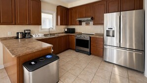 A kitchen with wooden cabinets, a stainless steel refrigerator, a built-in oven, and a coffee maker. - Private Queen Bed w/Mini Fridge, 2.5 Baths—Brampton Shared Home near GO Station! (Brampton)