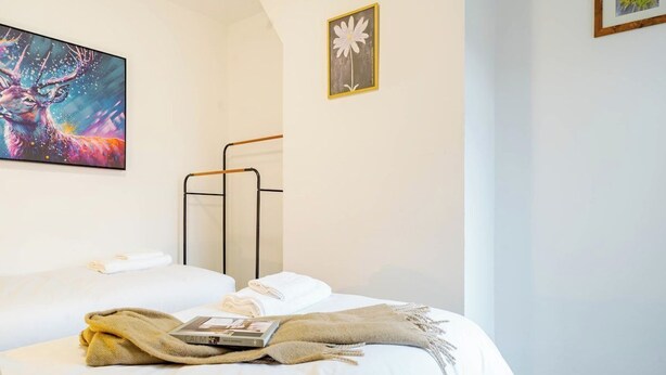 A hotel room with a bed, a painting, and a framed picture on the wall. - Modern 3 Bedroom House | WA10 | Central St. Helens (St Helens)