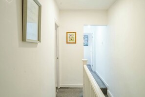 Ein Flur mit einer Tür am Ende, einem gerahmten Zitat an der Wand und einem kleinen, gerahmten Bild.