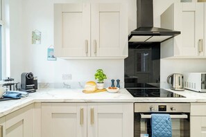 Een moderne keuken met witte kastjes, een zwarte kookplaat en een magnetron.