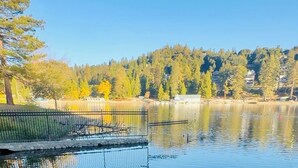 A serene lakeside view with a dock, trees, and a clear sky.