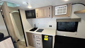 A compact kitchenette with a microwave, sink, and refrigerator.