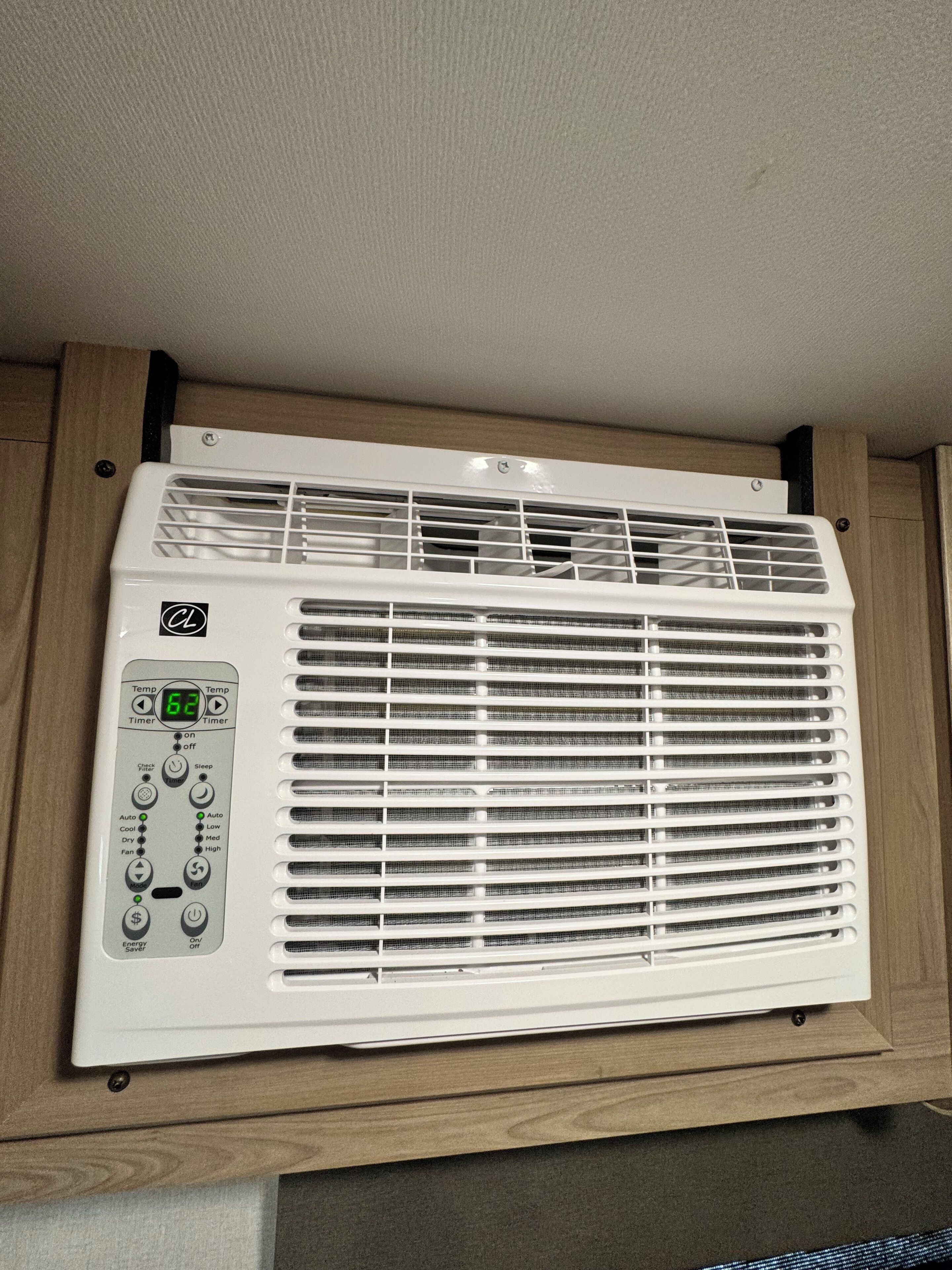 Un acondicionador de aire portátil blanco con pantalla digital y panel de control, sobre una superficie de madera.