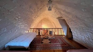 An attic bedroom with a wooden floor, two beds, a patterned rug, and a lantern. - Lou Castel - Medieval castle (Le Clapier)