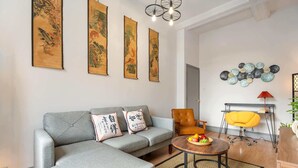 Een moderne woonkamer met een grijze bank, een ronde salontafel en een gele fauteuil.