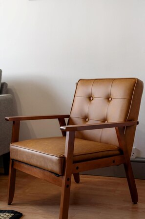 A single wooden chair with a cushioned seat and backrest, positioned on a wooden floor against a plain wall. - Stylish 2 BR Flat near Brick Lane, London Sleeps 4 (Greater London)