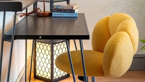 Een kamer met een moderne lamp, een gele stoel en twee schilderijen aan de muur.