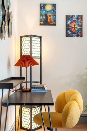 Ein Zimmer mit einer modernen Lampe, einem gelben Sessel und zwei Bildern an der Wand.