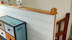 Une chambre avec un lit en bois, une commode à tiroirs et deux petits voiliers posés sur le dessus.