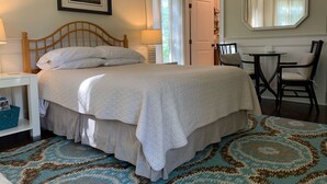 A neatly arranged bedroom with a large bed, bedside tables, a chair, and a mirror.