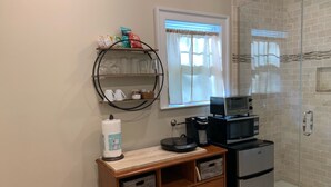 A compact kitchenette with a microwave, coffee maker, and storage drawers.