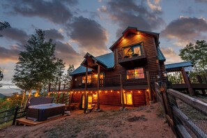 A log cabin with a balcony, a hot tub, and a deck area.