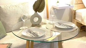 A dining area with a glass table, white plates, cutlery, a decorative leaf, a lamp, and a small vase with flowers. - W&D Living-Tête de Fleur-Balcony above Schloßarkaden (Brunswick)