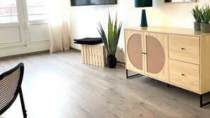 A modern living room with a flat-screen TV, a wooden cabinet, a potted plant, and a chair. - W&D Living-Tête de Fleur-Balcony above Schloßarkaden (Brunswick)