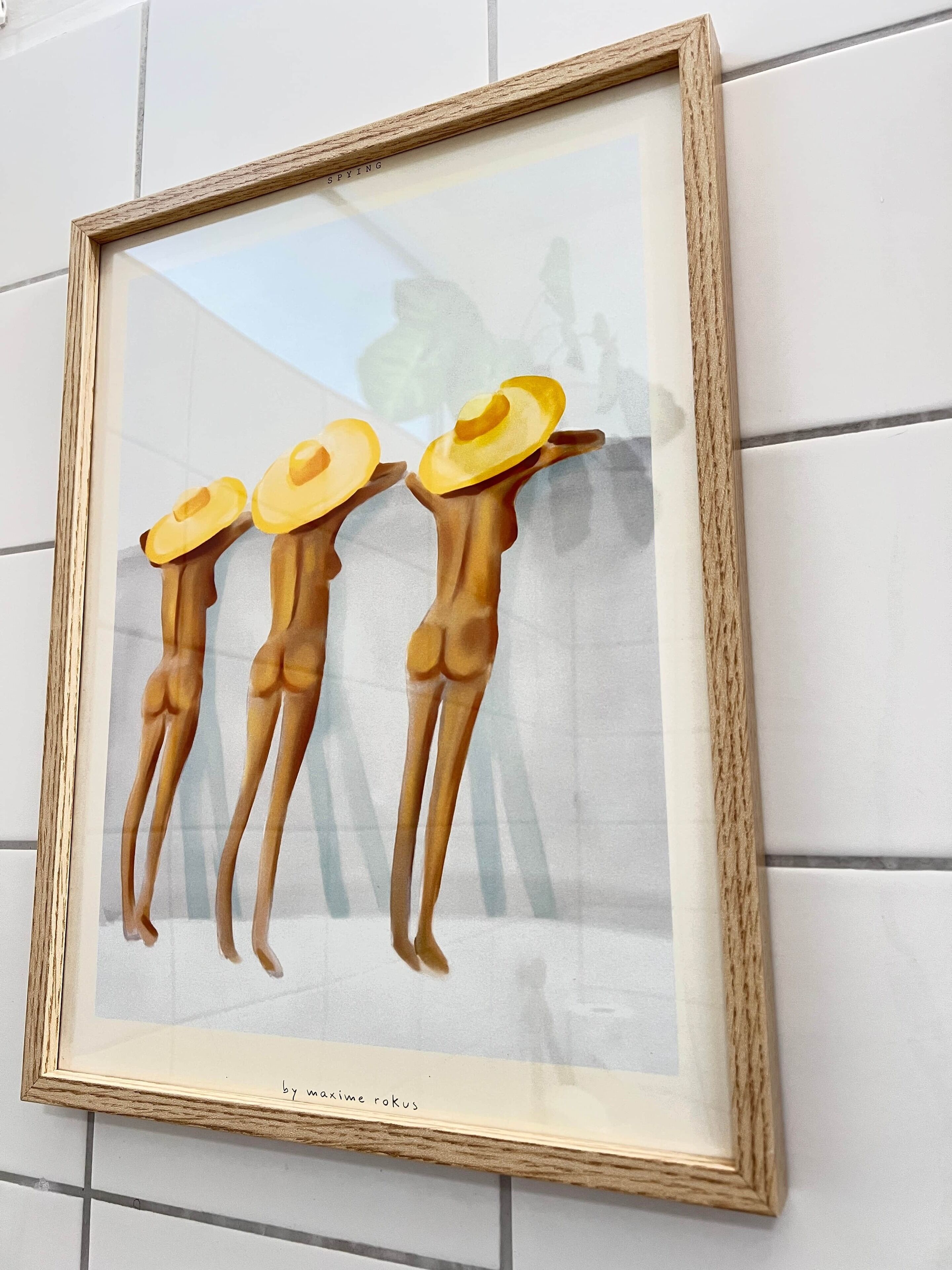 A framed artwork of three figures with hats on a tiled wall.