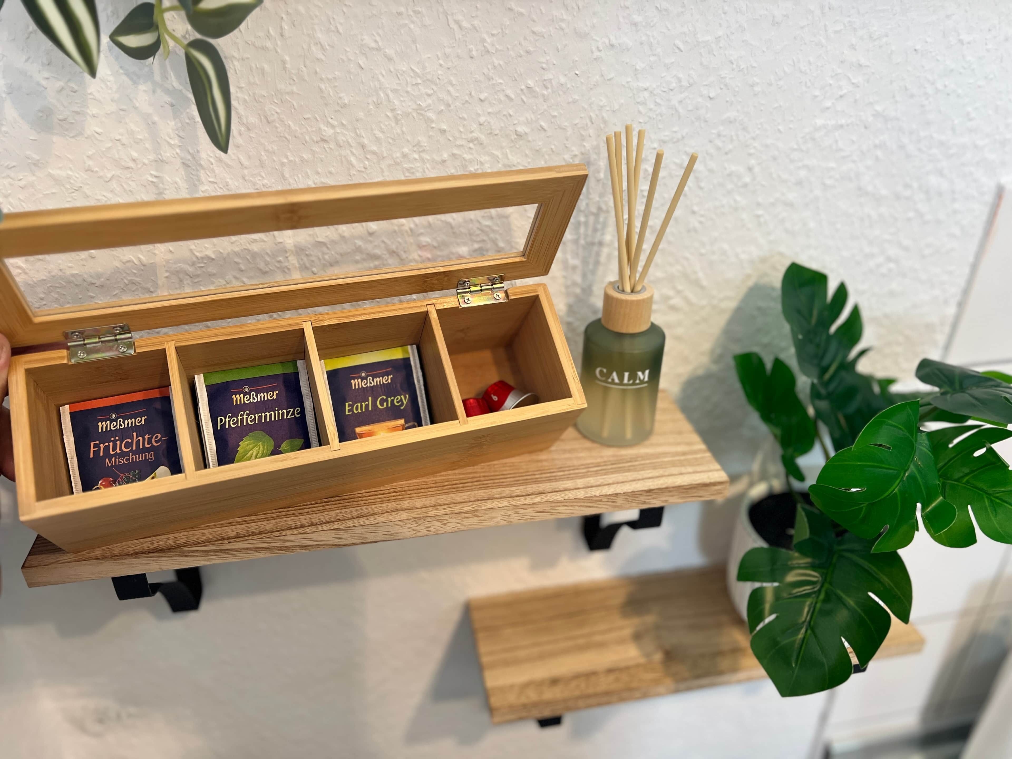 Una caja de madera con divisiones que contiene cajas de té y un difusor.
