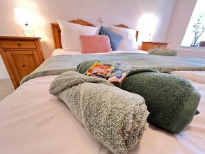 Cama bem arrumada com almofadas, mesa de cabeceira com abajur e janela com vista.