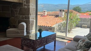 Ein Wohnzimmer mit Kamin aus Stein, einem Glastisch und einer Couch.