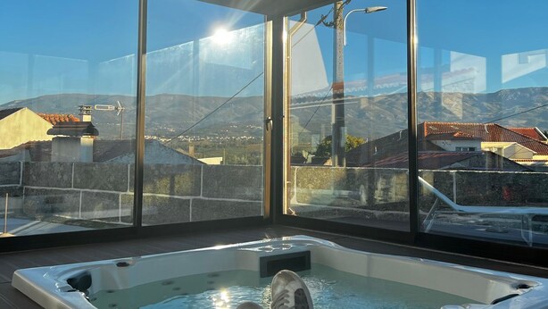 Ein Whirlpool mit freiem Blick auf die umliegende Landschaft durch große Fenster.