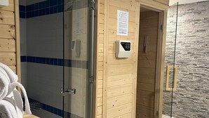 Ein Holzsauna-Raum mit Glastür, Handtuchhalter und Bedienfeld an der Wand.