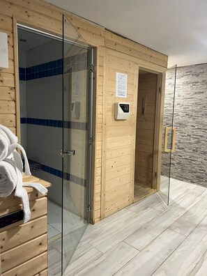 A wooden sauna room with a glass door, a towel rack, and a control panel on the wall. - Exclusive House in Serra da Estrela with Private Spa for Moments of Relaxation (Lagarinhos)