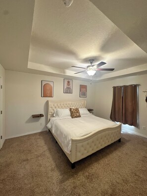A bedroom with a large bed, a ceiling fan, and a window with curtains. - 3-bedroom house in serene Davenport with cool AC! (Davenport)
