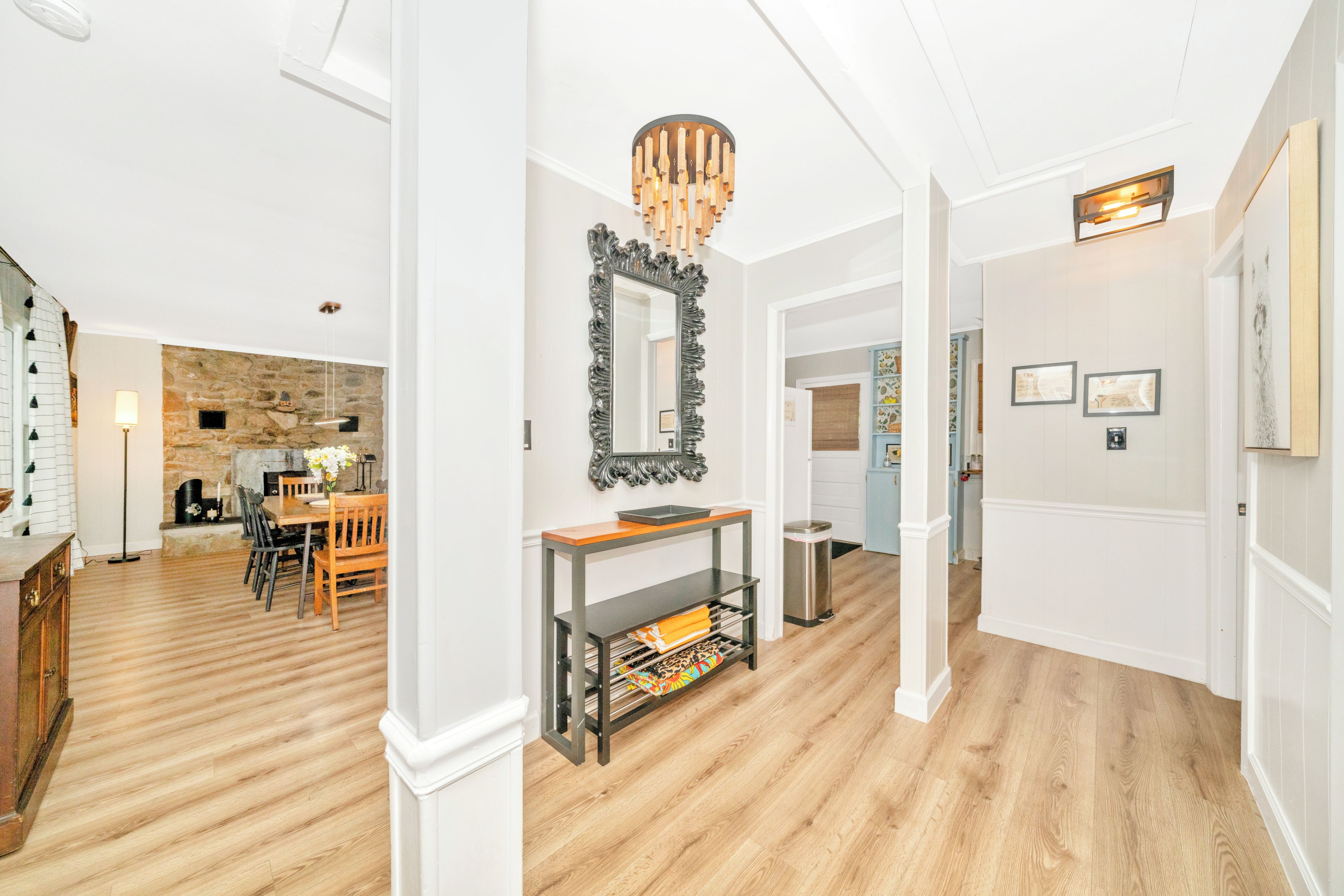 A spacious hallway with a wooden floor, a stone wall, and a dining area with a table and chairs.
