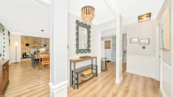 A spacious hallway with a wooden floor, a stone wall, and a dining area with a table and chairs.