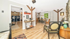 Amplia sala de estar con piso de madera, una mesa de comedor, sillas, una mesa de centro y un ventilador de techo.