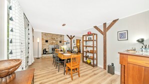 Una cocina amplia con piso de madera, un comedor con mesa y sillas de madera, y una pared de acento de piedra.