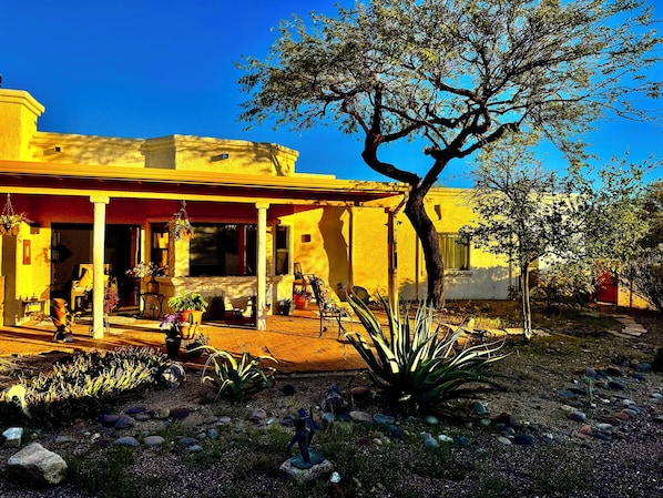 A yellow building with a covered patio, surrounded by rocks and plants. - La Paloma Mountain Suite nestled within an estate in Tucson’s Catalina Foothills (Tucson)