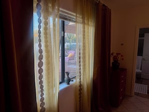 A room with a window covered by sheer curtains, a vase with flowers on a cabinet, and a tiled floor. - La Paloma Mountain Suite nestled within an estate in Tucson’s Catalina Foothills (Tucson)