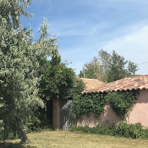 A house with a tiled roof, a garden with a large tree, and a gate. - Maylou Baan, family home on the Etang de Thau, 3 kilometers from the sea (Marseillan)