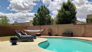Un jardin avec une piscine, des chaises longues et un mur en briques.