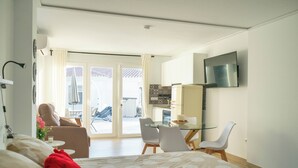 A hotel room with a bed, a glass table, two chairs, a TV, and a view of the outside. - Costa del Sol Villas - Bedroom with Private Bathroom 1 (Benajarafe)